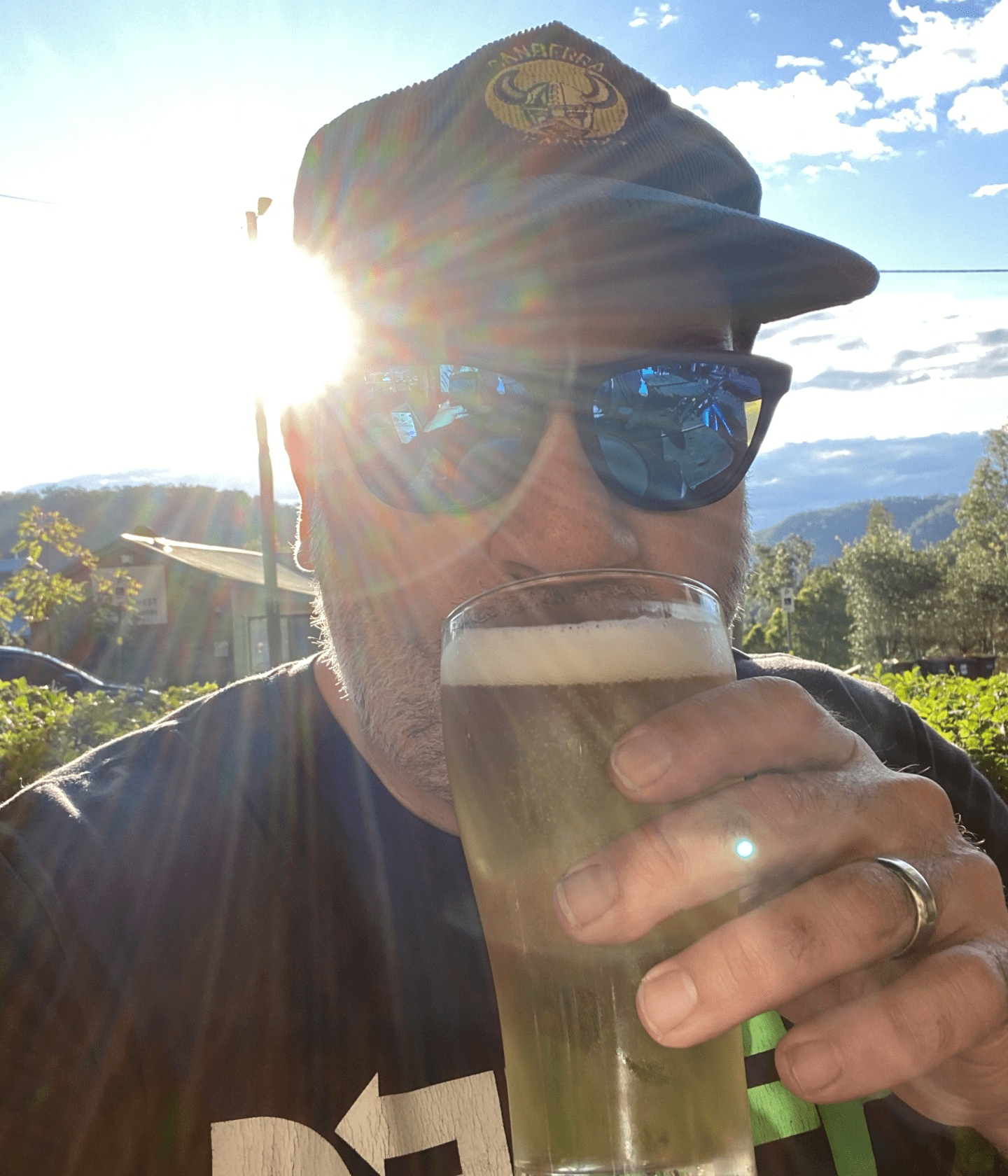 Man wearing sunglasses drinking beer outdoors.
